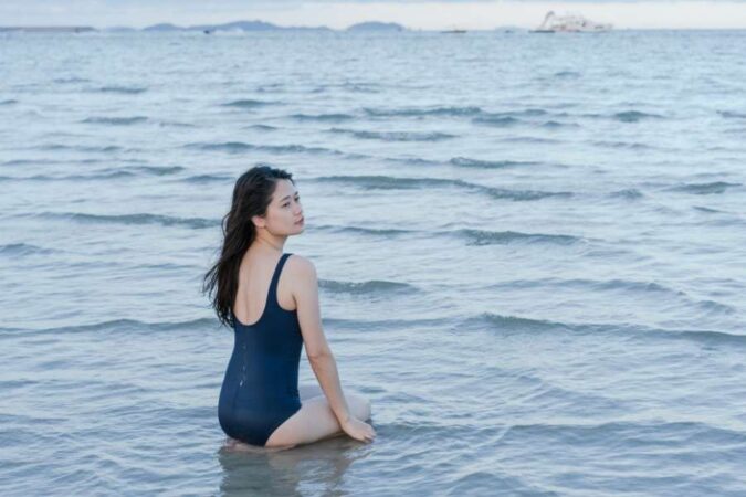 Une jeune femme assise sereinement dans l'eau de mer calme par une journée ensoleillée.